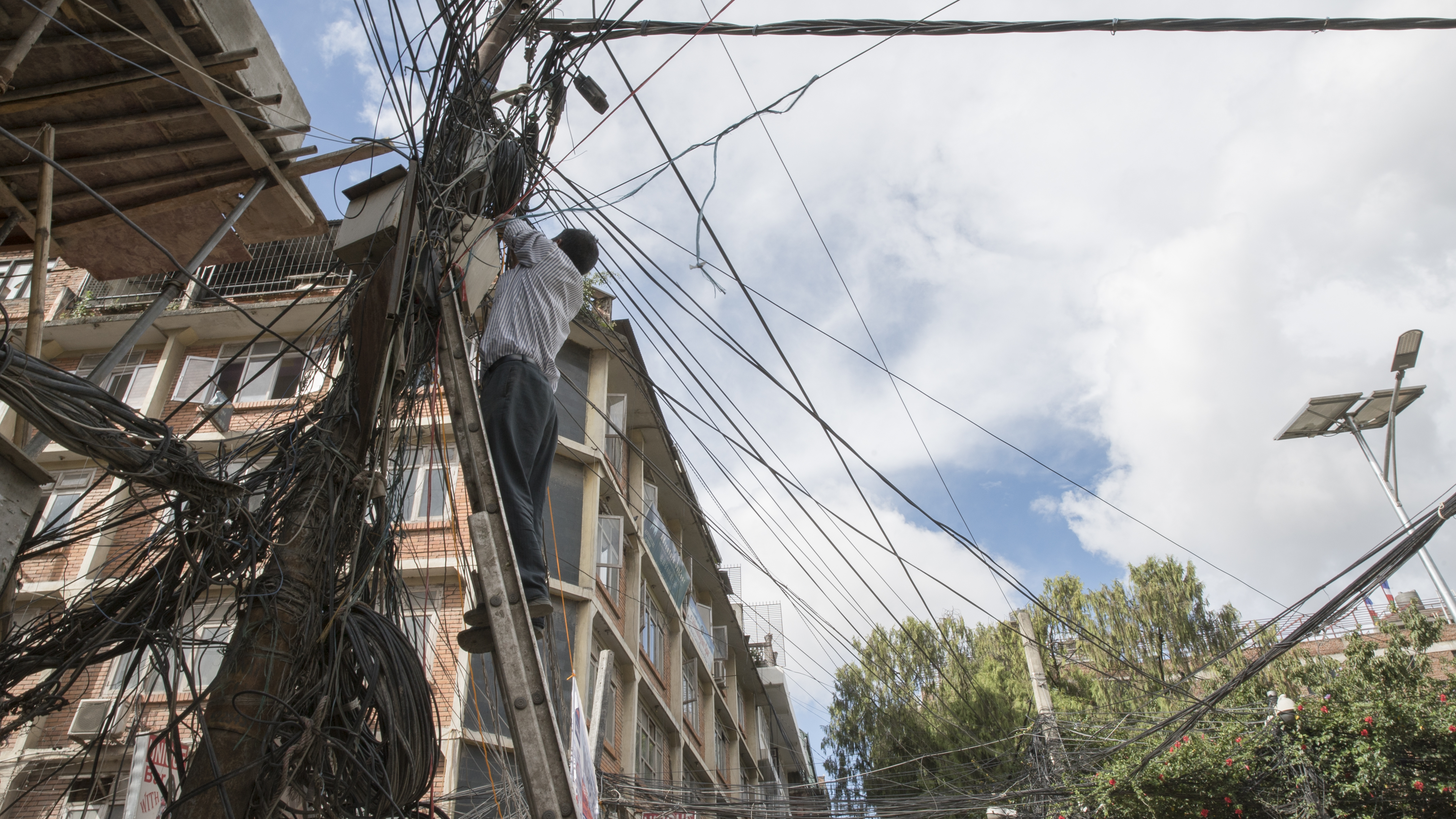 Electrician works on power lines at an intersection in Kathmandu, Nepal.